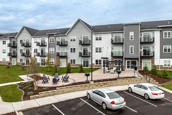 an exterior view of an apartment building with cars parked in a parking lot